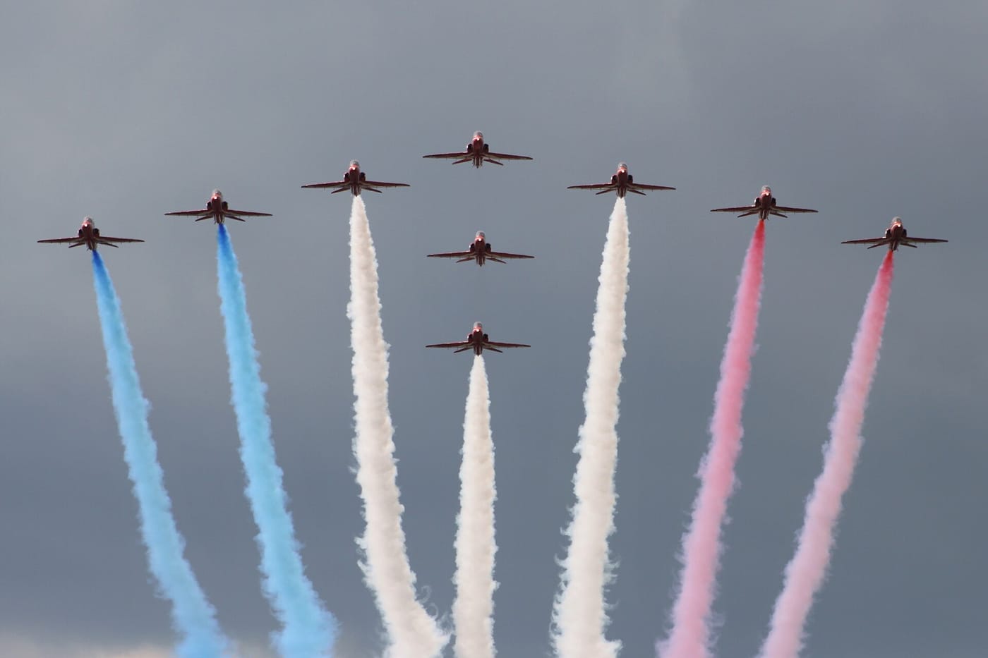 The Red Arrows in formation trailing red, white and blue smoke at RAF Waddington