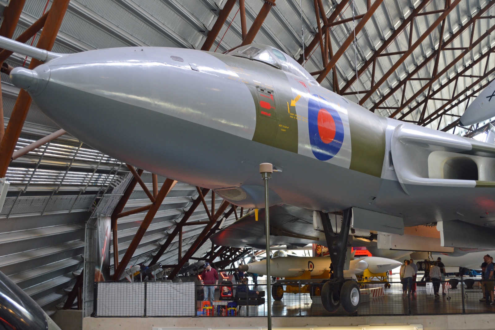 A grey-green camouflaged Avro Vulcan delta bomber parked inside a museum hall