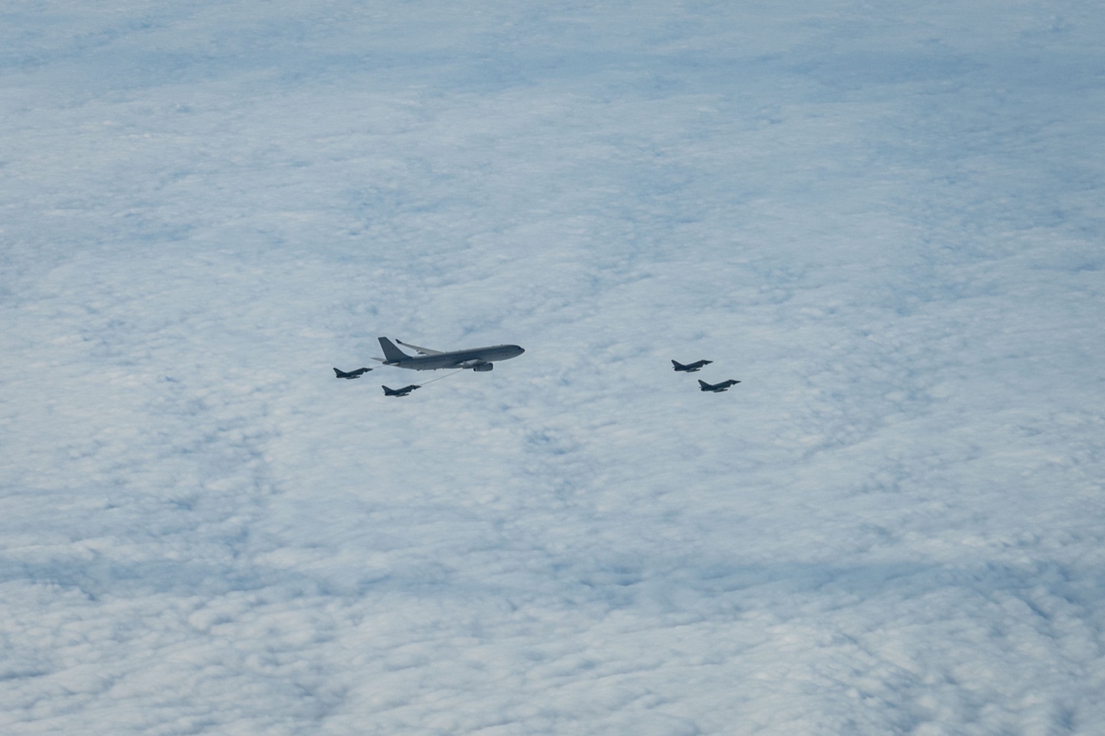 An Airbus Voyager tanker above a cloud sheet with a Typhoon on its hose and three more Typhoons nearby