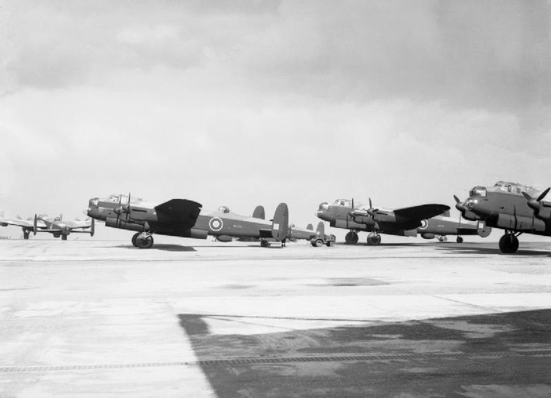 A row of newly built Lancaster bombers parked on a concrete apron under an overcast sky