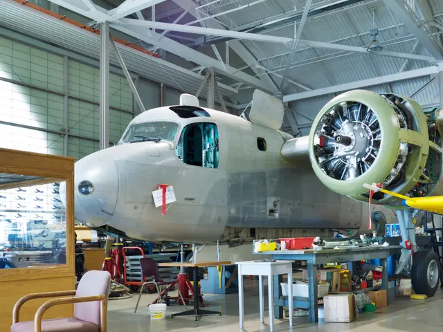 Grey Grumman Tracker anti-submarine aircraft with an exposed radial engine, surrounded by workbenches in the restoration area