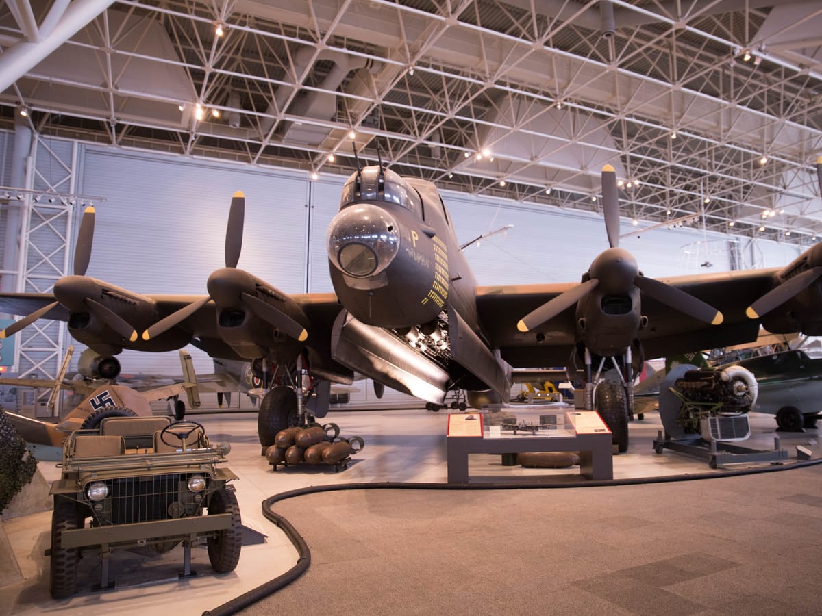 Avro Lancaster X bomber KB944 in dark green and brown camouflage, seen from the front under the museum's white steel roof trusses
