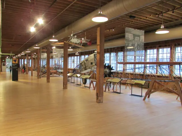 Long timber-pillared factory floor with wooden aircraft parts and period tools on display