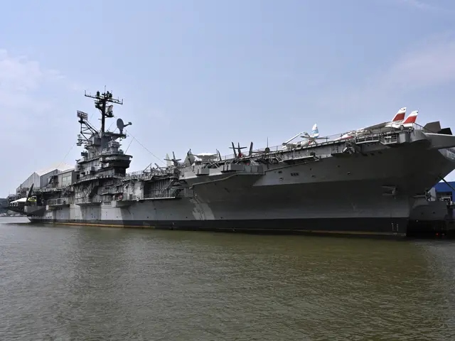 The grey aircraft carrier Intrepid moored on the Hudson, its island superstructure at left and jets parked along the flight deck